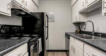 A kitchen with a black refrigerator and white cabinets.