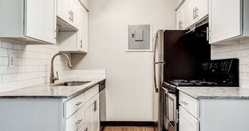 A kitchen with white cabinets and a black refrigerator.