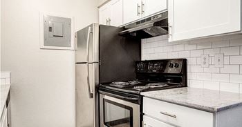 A black stove top oven sits next to a black refrigerator in a kitchen.