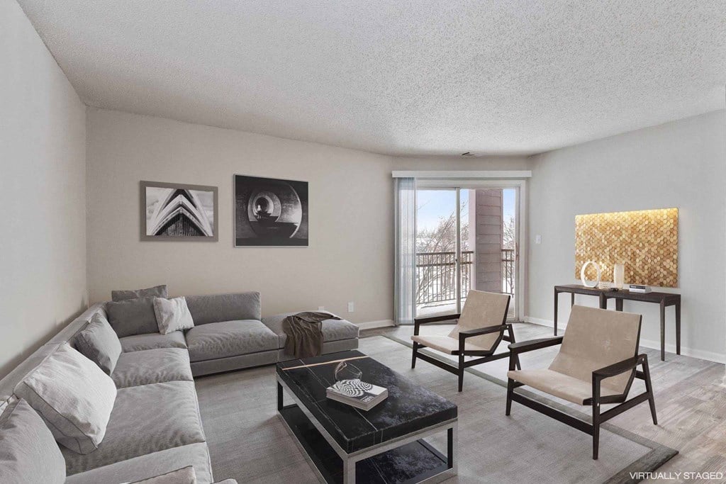 A living room with a grey couch, a coffee table, and two chairs.