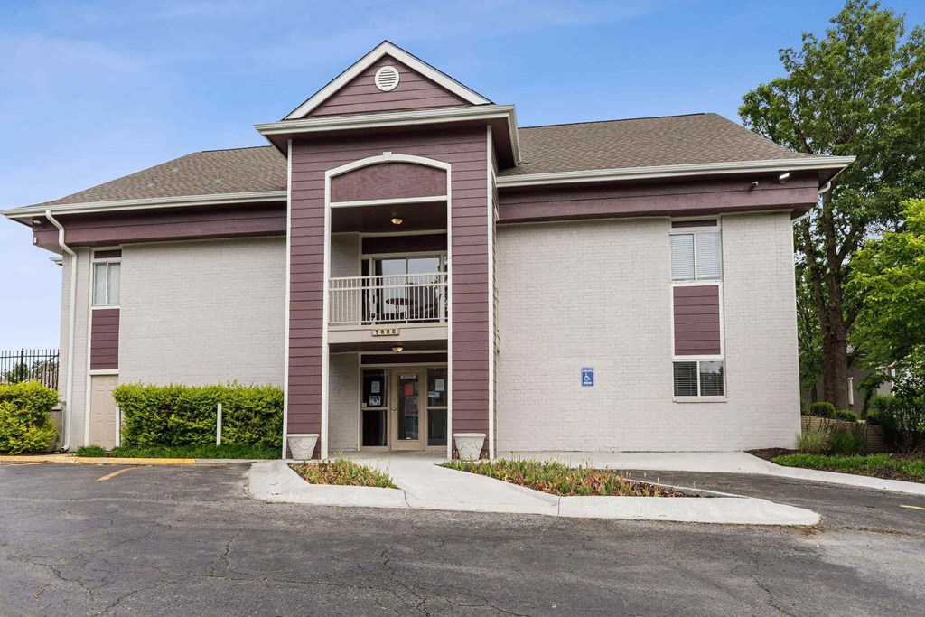 A building with a brown roof and a large entrance with a balcony.