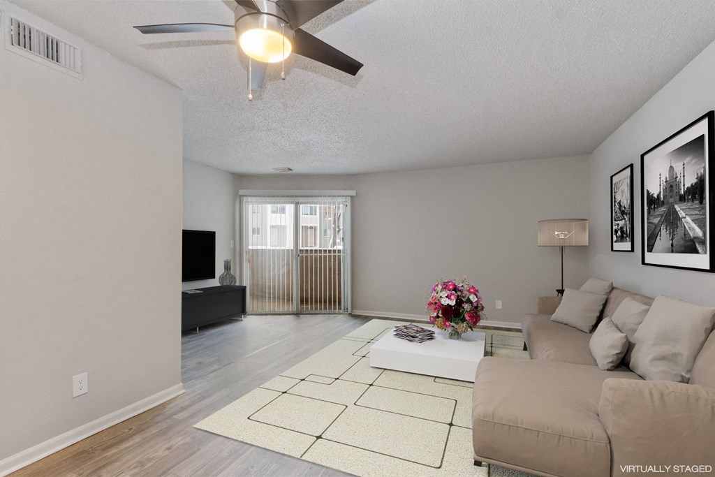 A living room with a couch, a coffee table, and a ceiling fan.