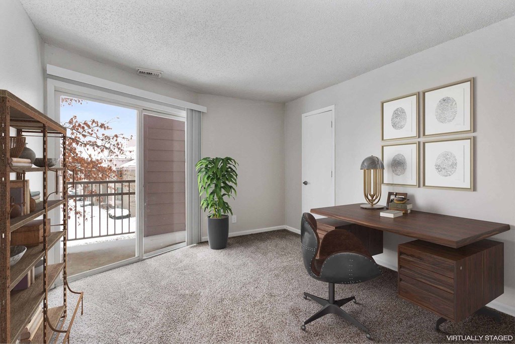 A room with a desk, chair, and a plant.