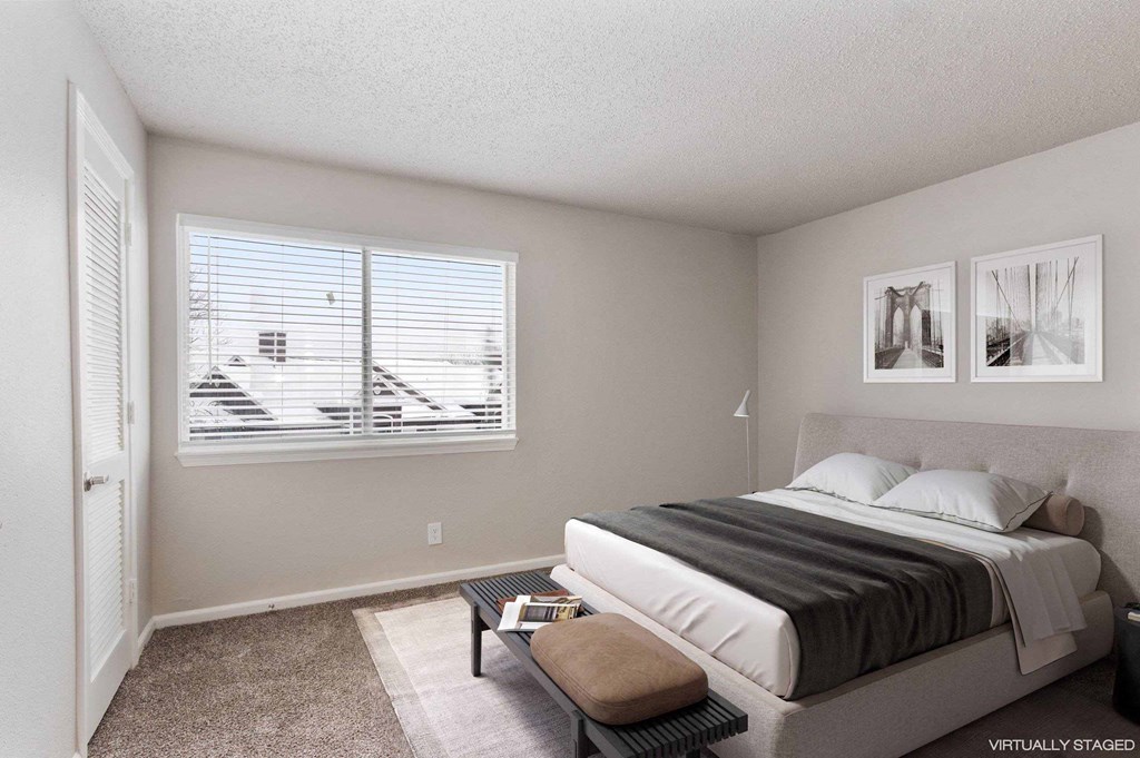 A bedroom with a bed, a bench, and pictures on the wall.