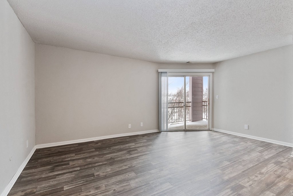 A room with wooden flooring and a sliding glass door.