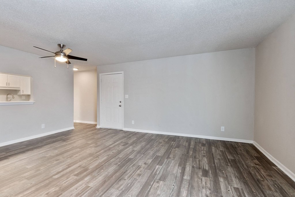 A room with a ceiling fan and wooden flooring.