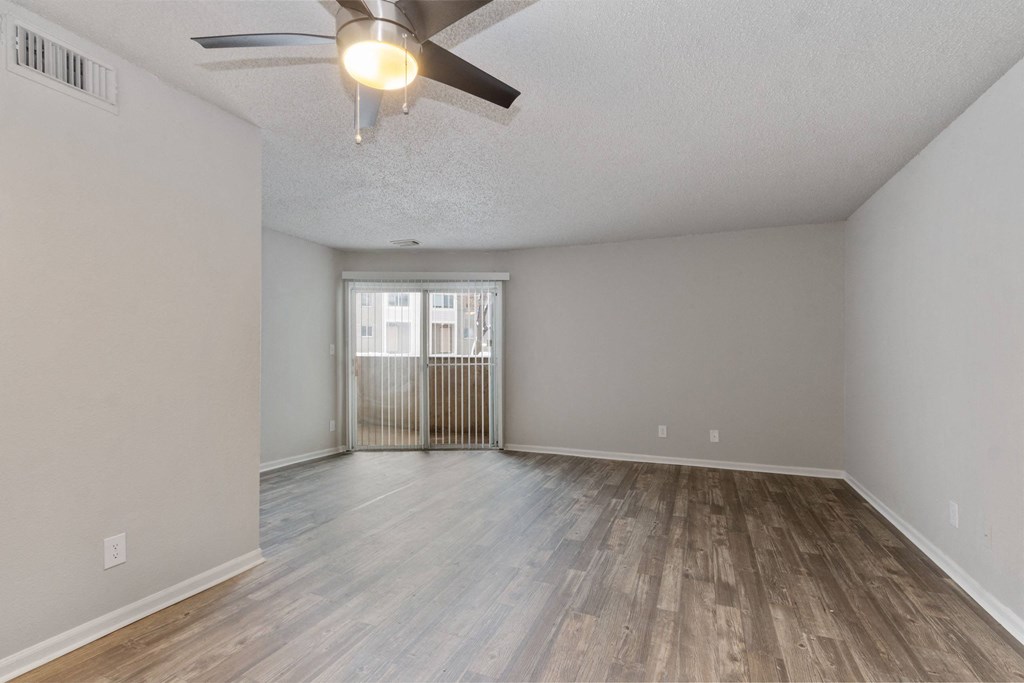 A room with a ceiling fan and wooden flooring.