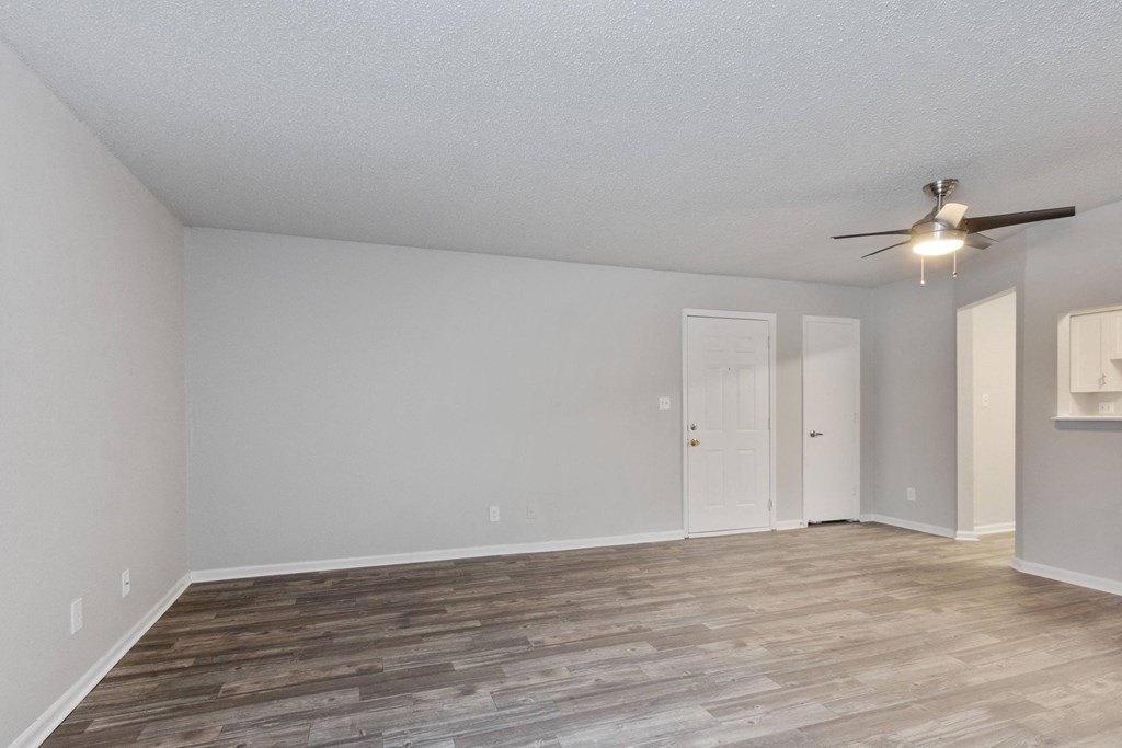A room with a ceiling fan and wooden flooring.
