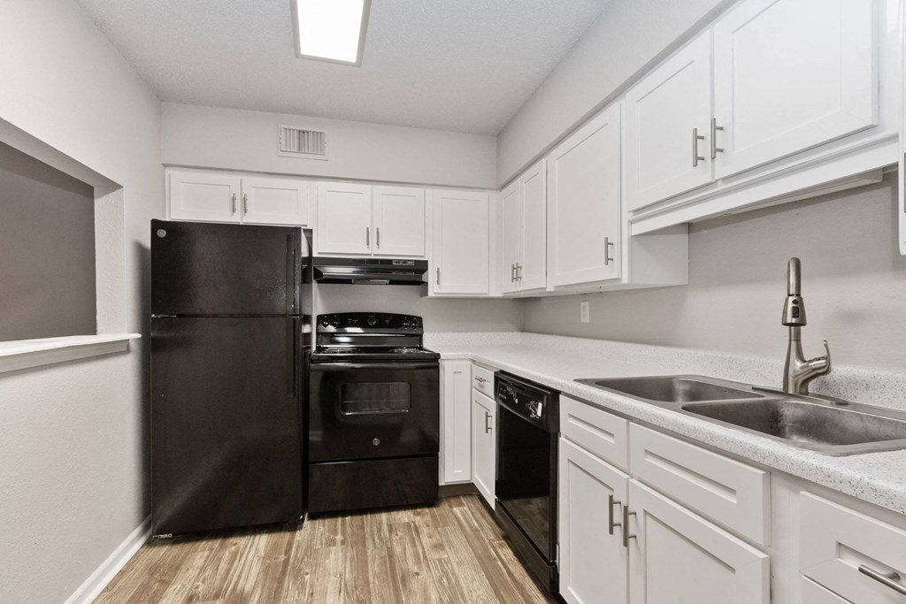 A kitchen with black appliances and white cabinets.
