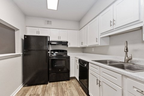 A kitchen with black appliances and white cabinets.