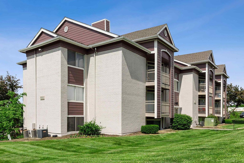 A large apartment complex with multiple balconies and a green lawn in front.