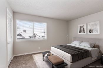 A bedroom with a bed, window, and two pictures on the wall.