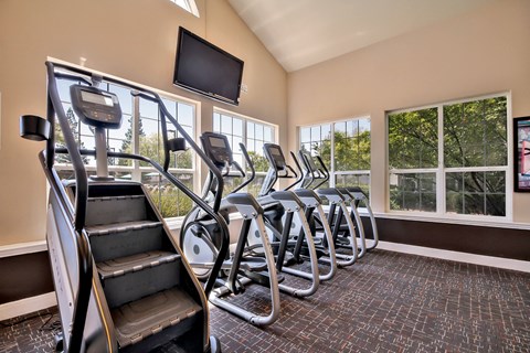 Fitness center with cardio equipment and windows at Rosemeade Apartments, Roseville