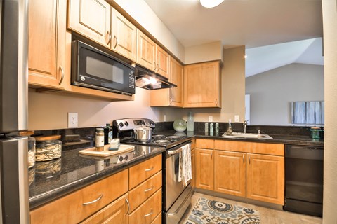 Modern kitchen with black appliances and dark countertops at Rosemeade Apartments, Roseville