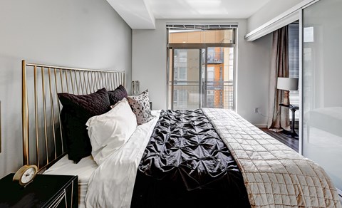 A bedroom with a large bed and a window overlooking a balcony.