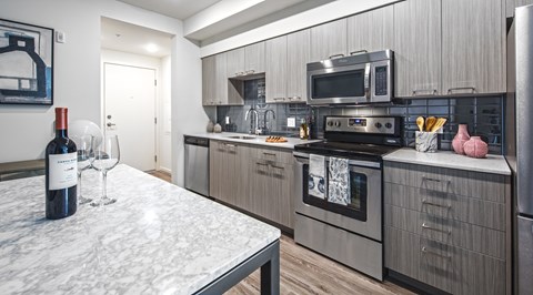 A kitchen with a marble table and modern appliances.