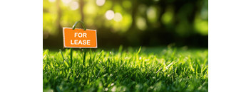 A lease sign is placed on a green lawn.