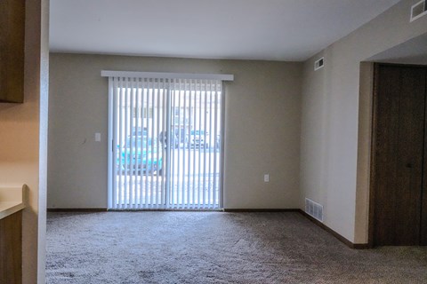 A room with a carpeted floor and a sliding glass door.