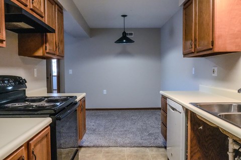 A kitchen with a black stove top oven and wooden cabinets.
