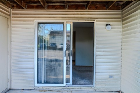 A white house with a sliding glass door and a brown wooden beam on the ceiling.