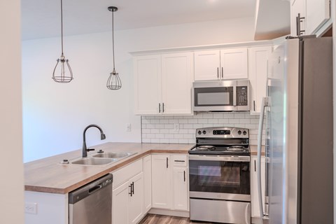 A kitchen with a stainless steel refrigerator and a microwave above the stove.