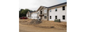 A row of houses under construction with a red truck parked in front of the first house.