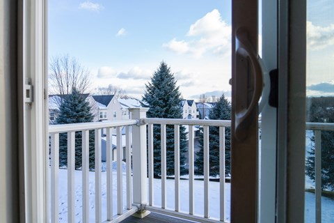 A view from a snowy balcony looking out at a residential neighborhood.