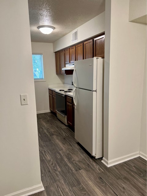 A kitchen with a white refrigerator and wooden cabinets.