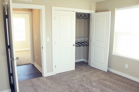 A room with a white door and a white closet with clothes hanging.