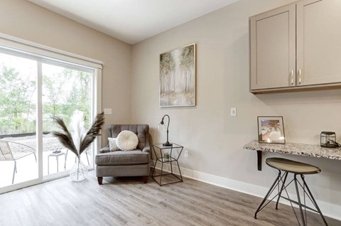A living room with a grey couch, a small table, and a painting on the wall.
