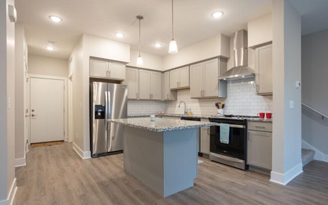 A kitchen with a stainless steel refrigerator and a range hood at Eden Forest Townhomes Apartments, Kentwood , Michigan