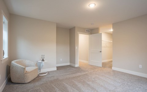A spacious room with a chair and a small table at Eden Forest Townhomes Apartments, Kentwood , 49508