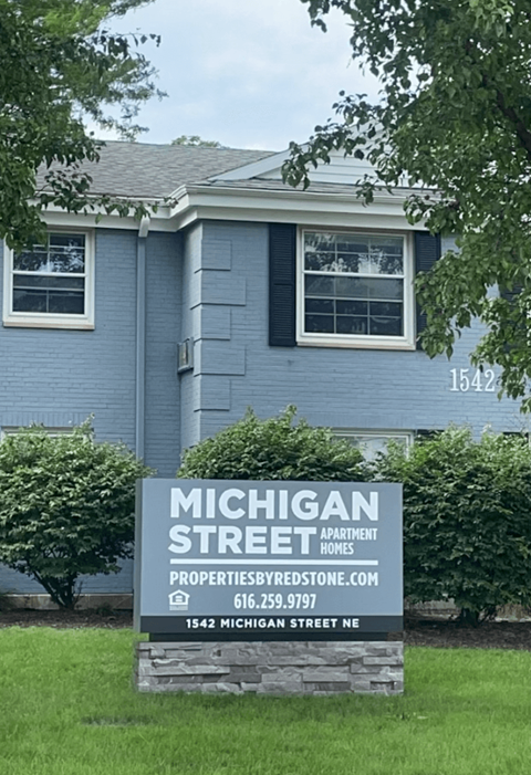 A blue house with a sign in front that says Michigan Street Apartment Homes at Michigan Street Apartment Homes, Michigan, 49503