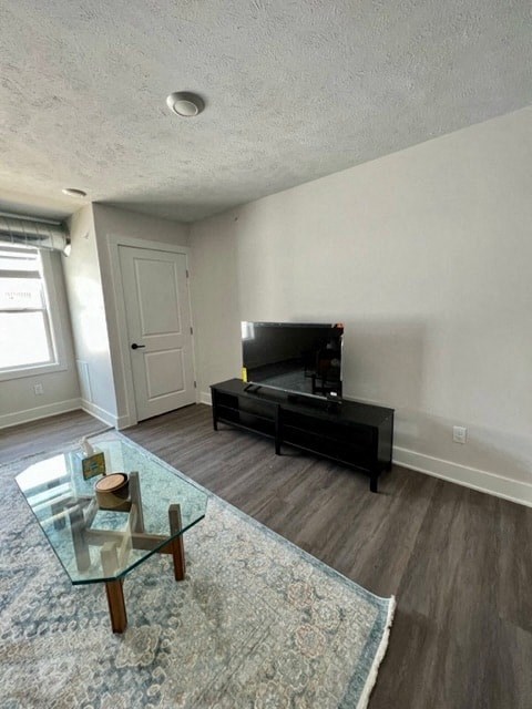 A living room with a glass coffee table and a black entertainment center.