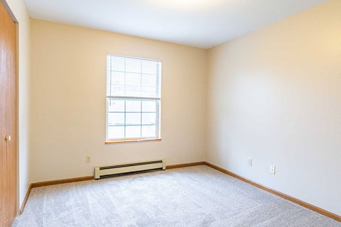 A room with a window and a carpeted floor.