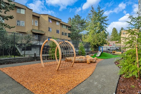 A playground with a swing set and a slide in the background of apartment buildings.
