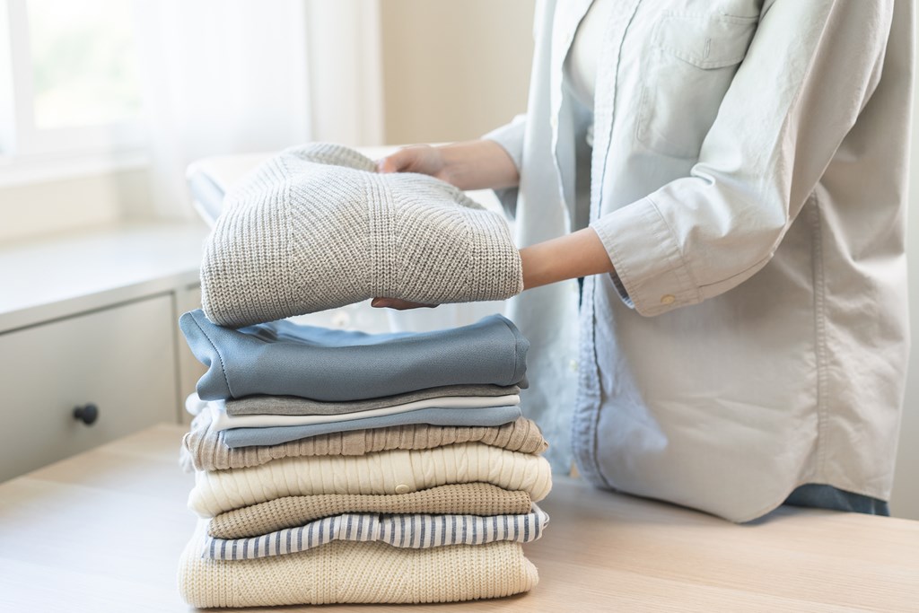 A person is holding a stack of folded clothes.