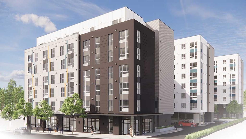 A modern multi-story building with a parking lot in front.