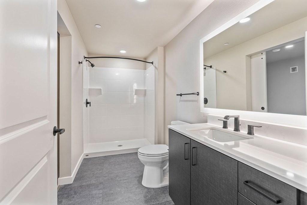 A white toilet is in a bathroom with a sink and mirror