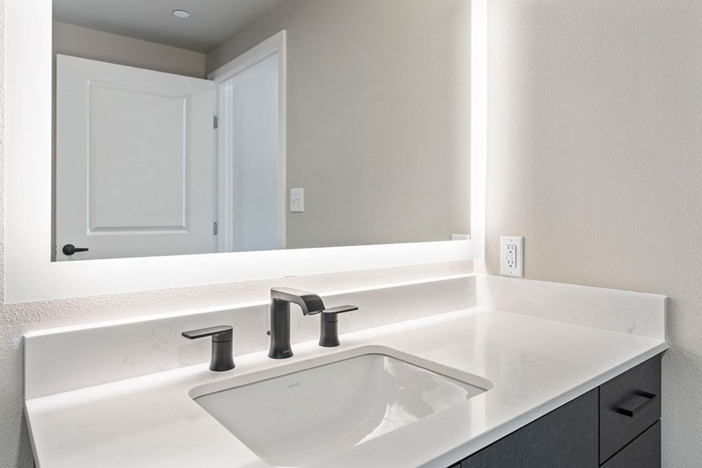 A white sink with two faucets is on a white countertop
