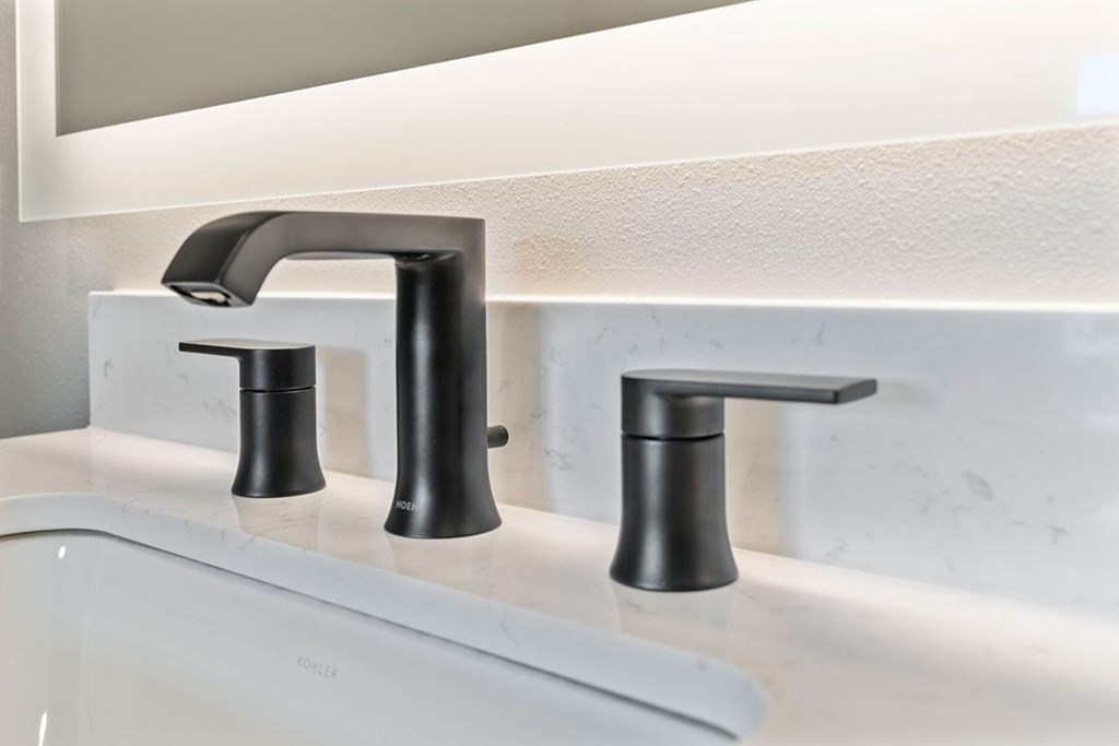 Two black faucets on a white sink