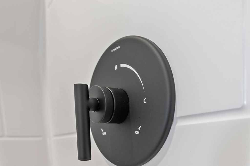 A black knob with the letters H, C, and ON is mounted on a white wall