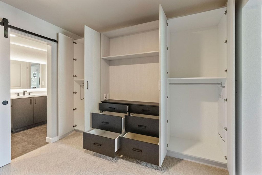 A white closet with drawers and shelves is open