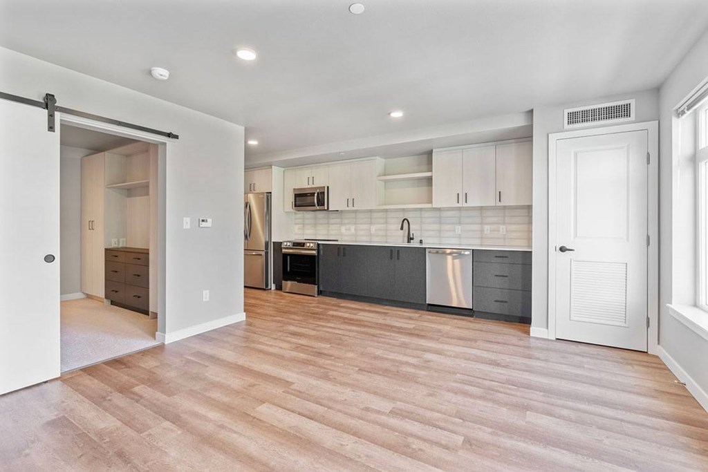 A kitchen with white cabinets and a wood floor