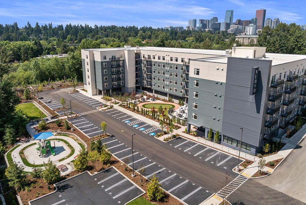 A parking lot in front of a large building with a pool.
