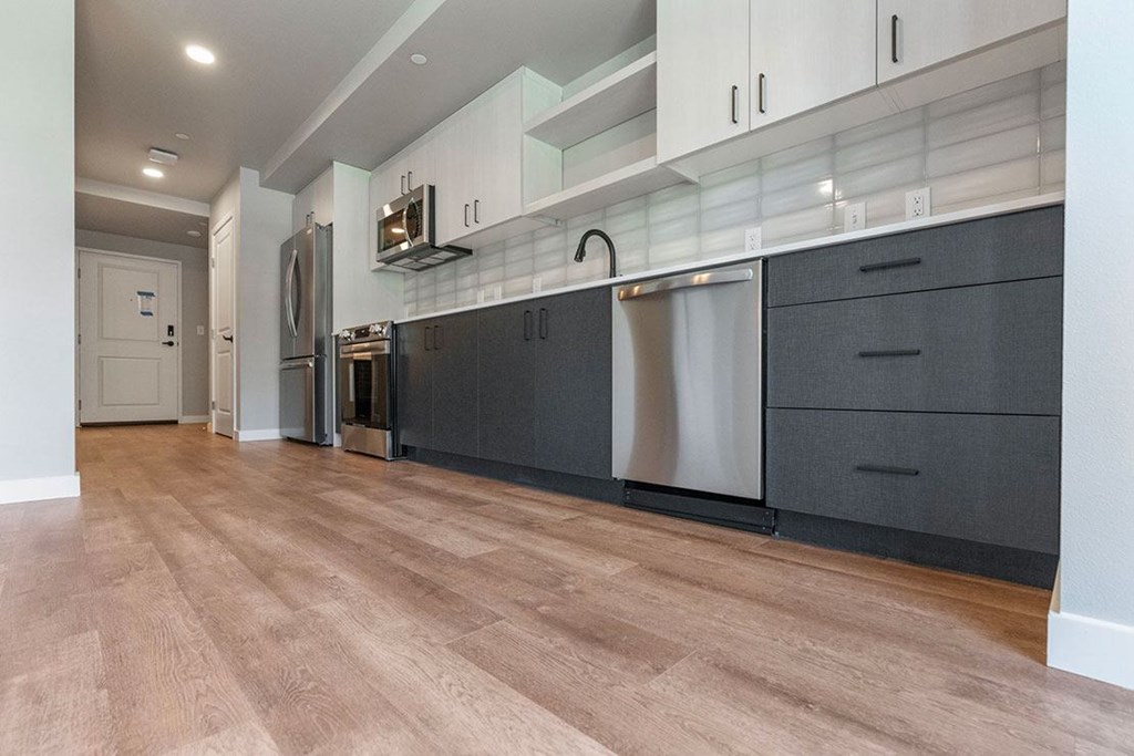 A kitchen with a stainless steel refrigerator, microwave, and oven.