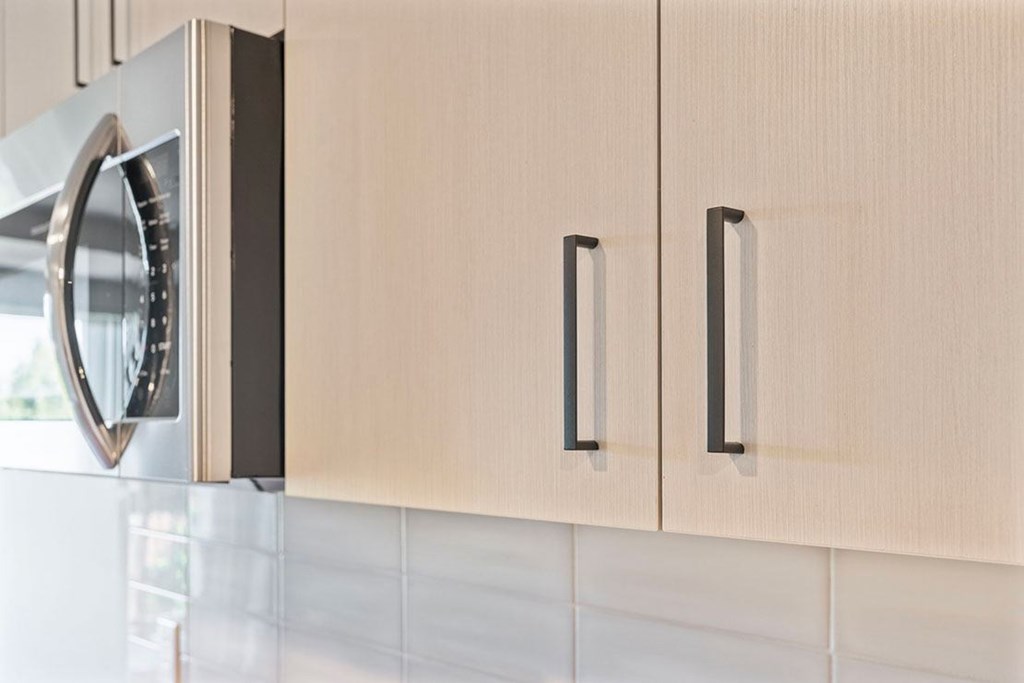 A microwave is installed above a light brown cabinet