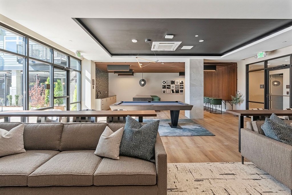A modern living room with a couch coffee table, and a view of the outdoors