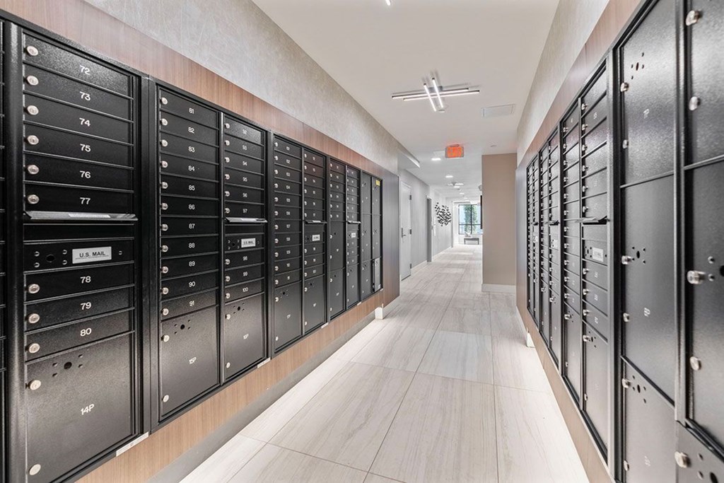 A long hallway with a series of black mailboxes on the wall