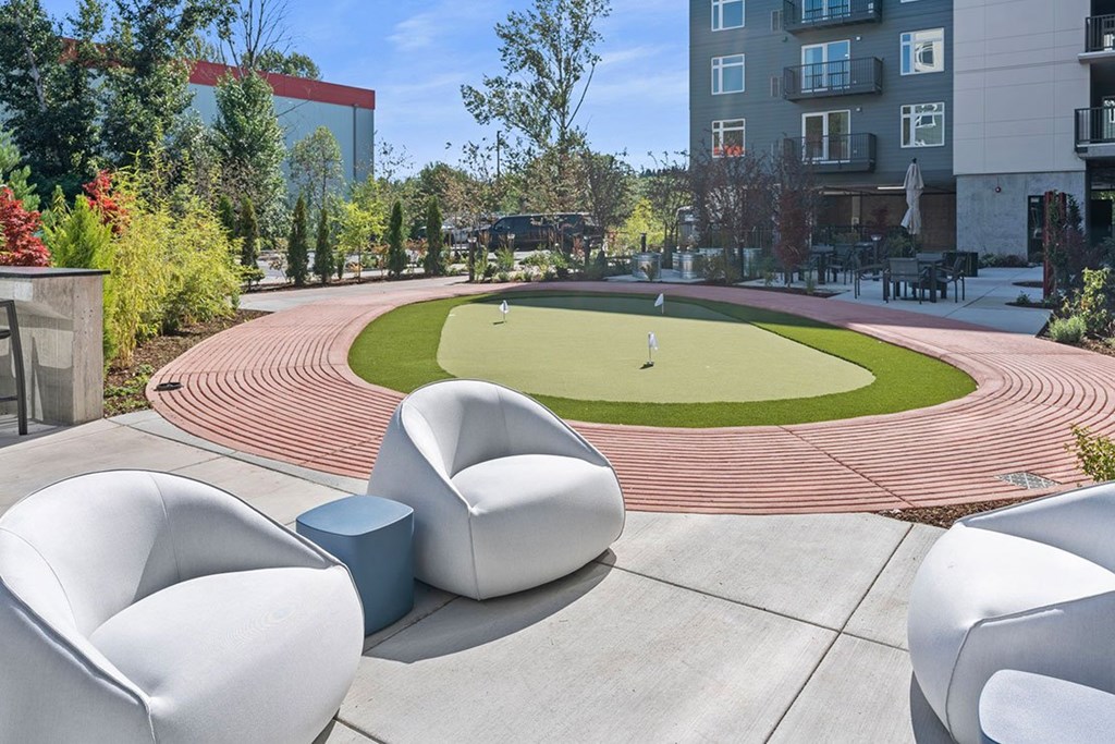A modern outdoor seating area with a grassy area and at track in the background.